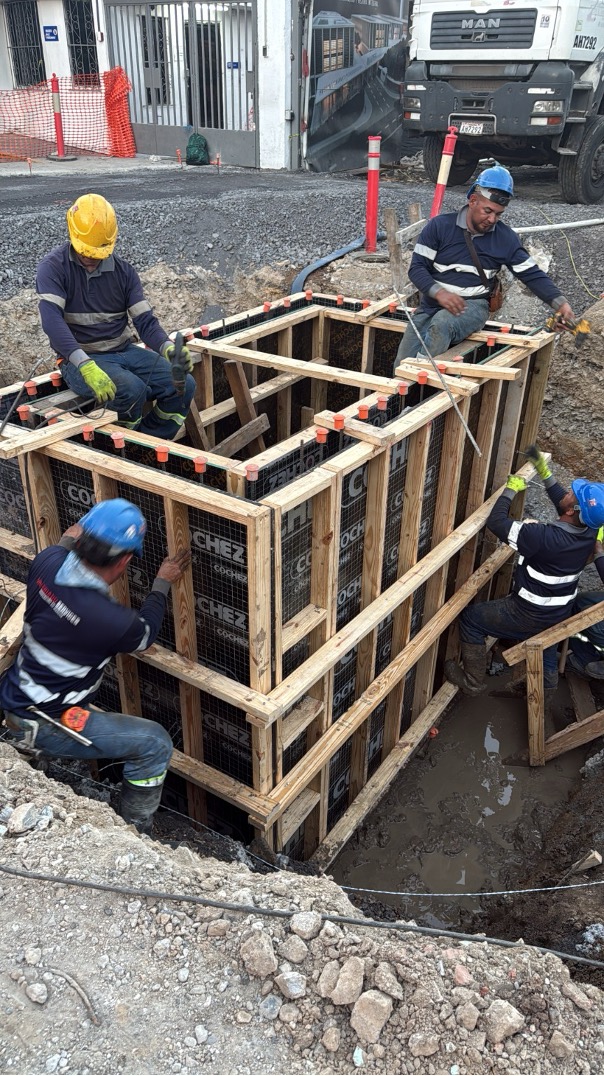 Cuadrilla de cuatro técnicos armando formaleta para cámara eléctrica subterránea