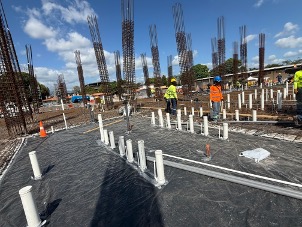 Losa con armadura preparada y conduits PVC, obreros con equipo de seguridad